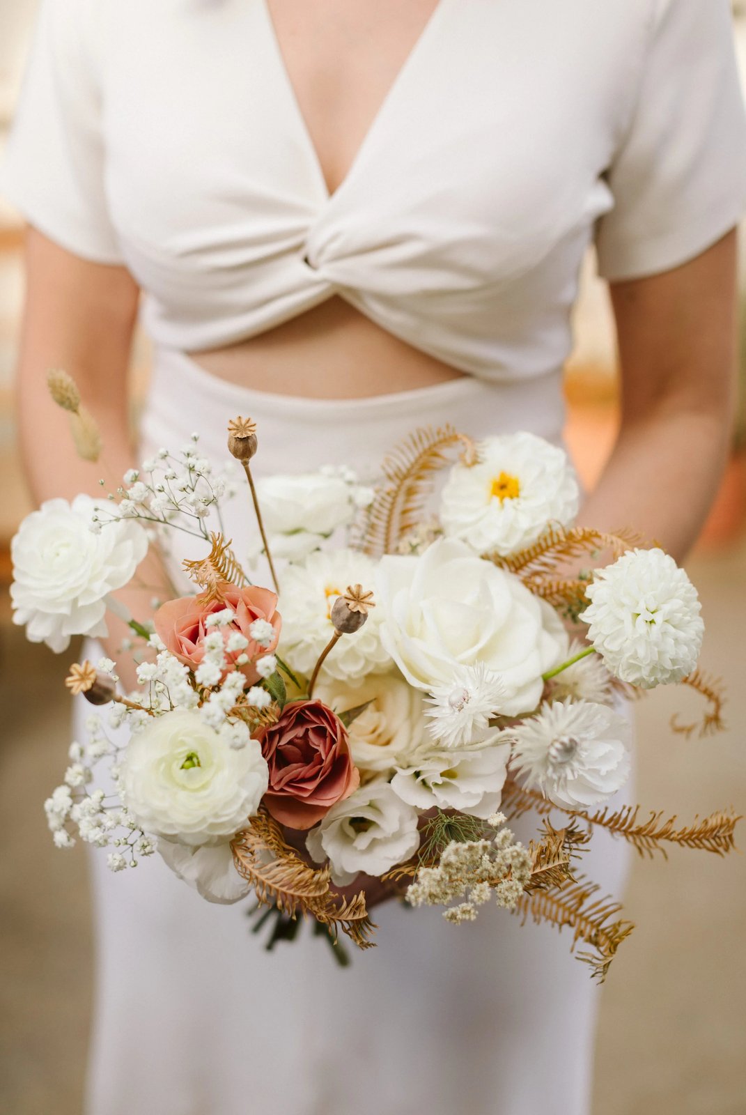Bride holding a garden-style white and rust bouquet