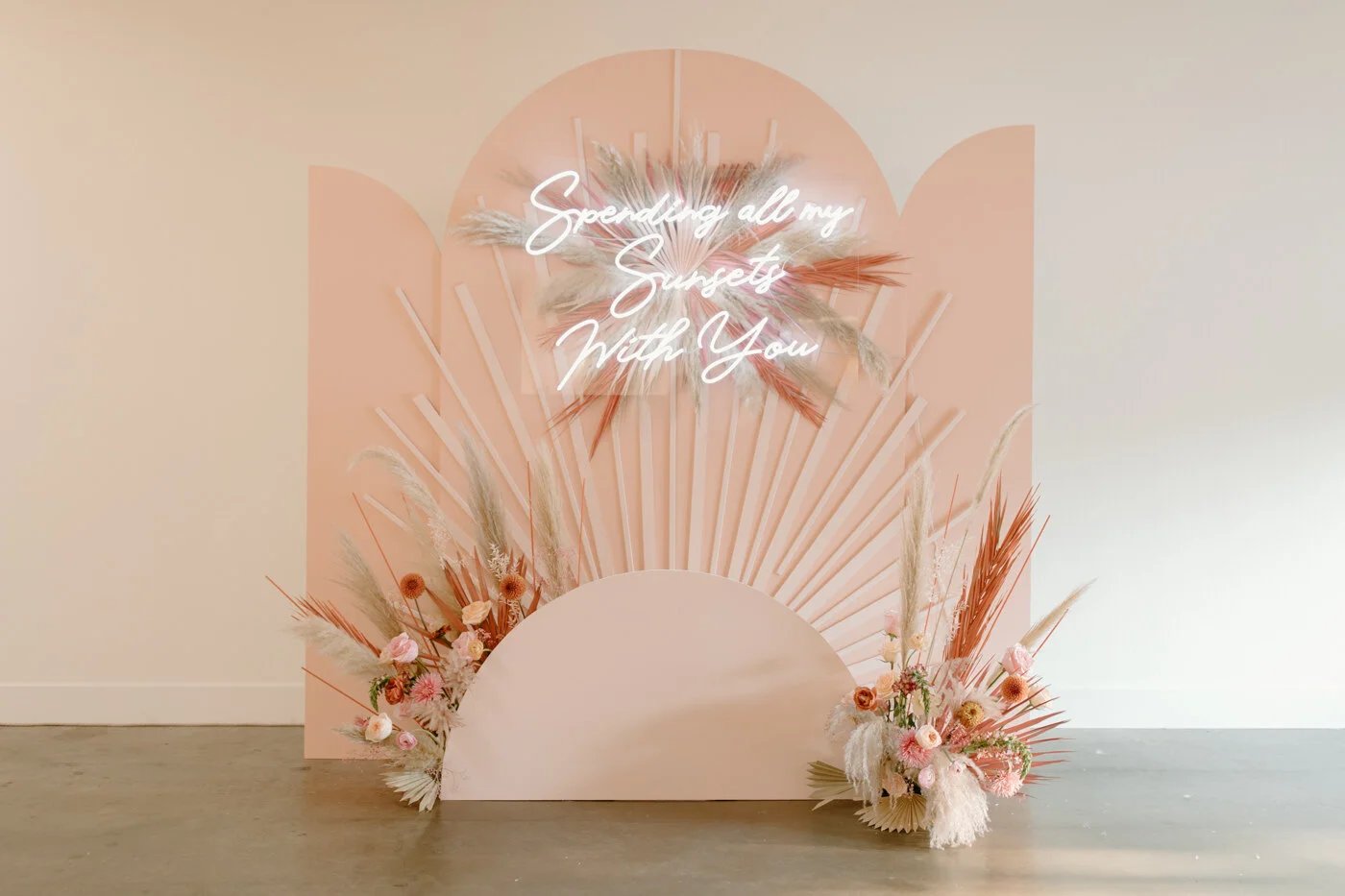 Whimsical arched backdrop with pampas and neon sign
